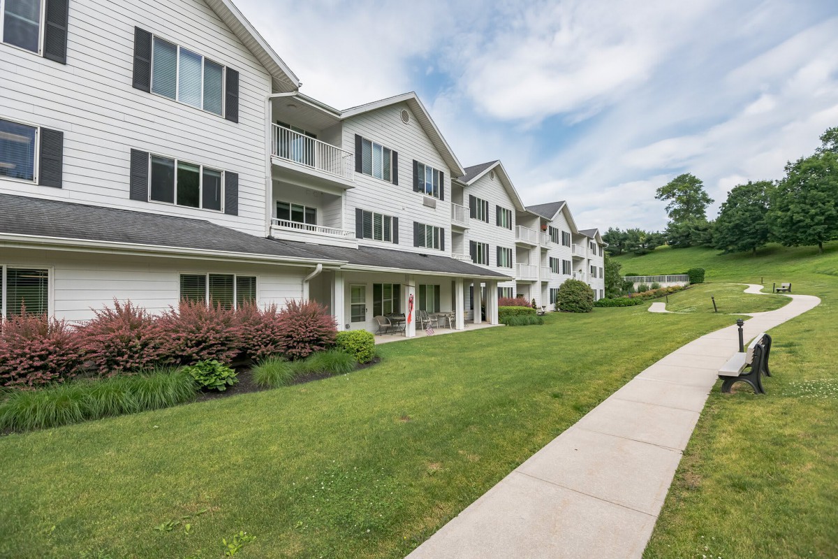 A view of a multi-story apartment building with a well-maintained lawn and pathway.