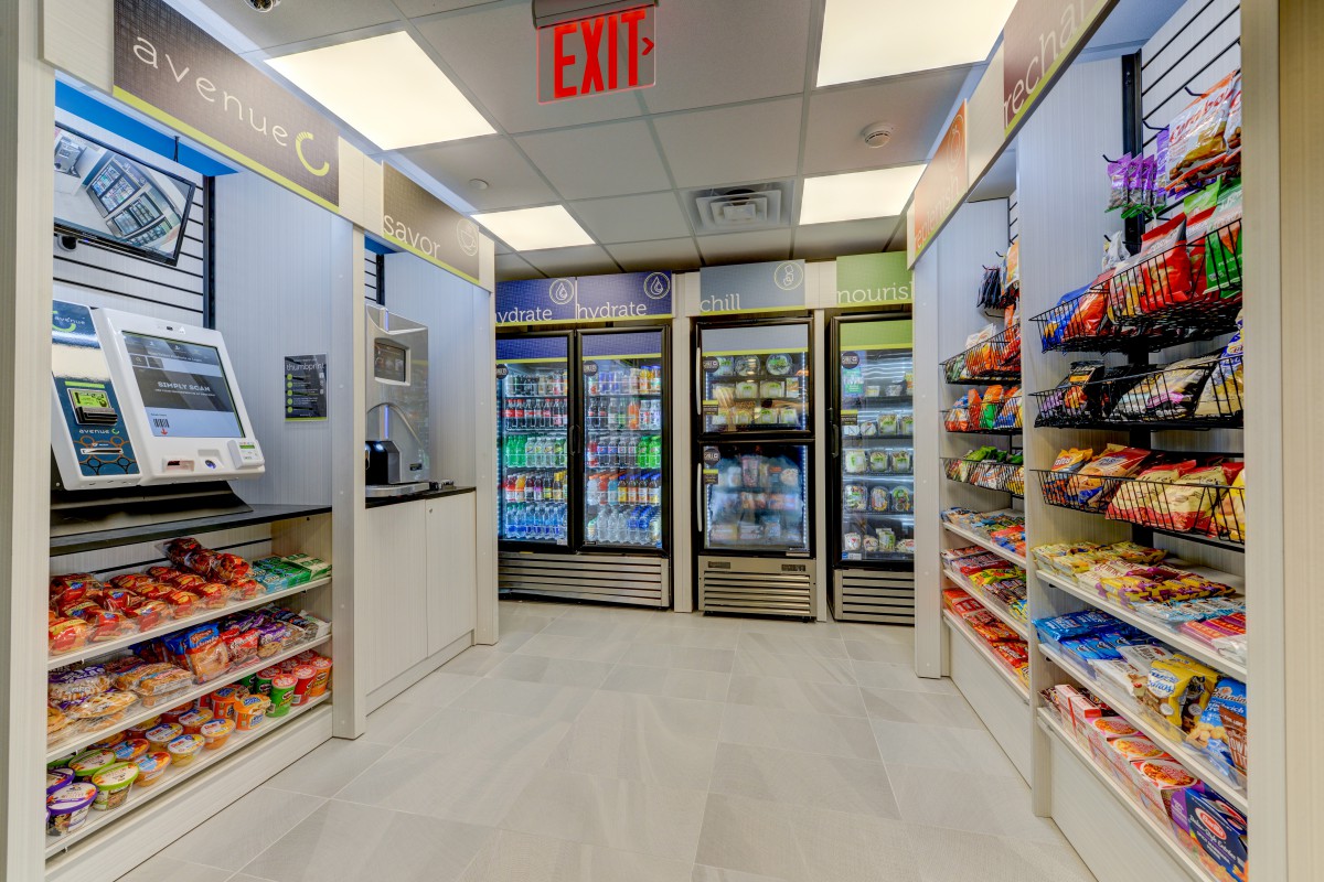 Interior of a convenience store with snack aisles and refrigerated beverage sections.