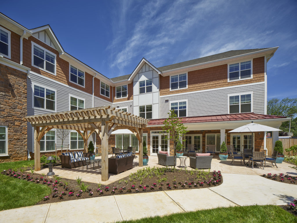 A modern residential building with outdoor seating and a pergola in the courtyard.