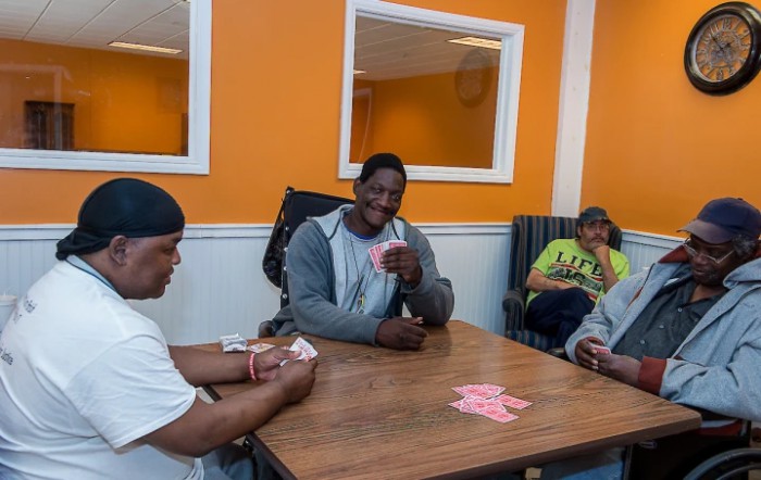 A group of people sitting around a table playing cards in a cozy indoor setting.