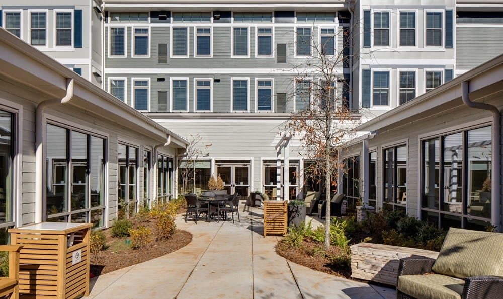 A modern courtyard with seating and landscaping surrounded by a multi-story building.