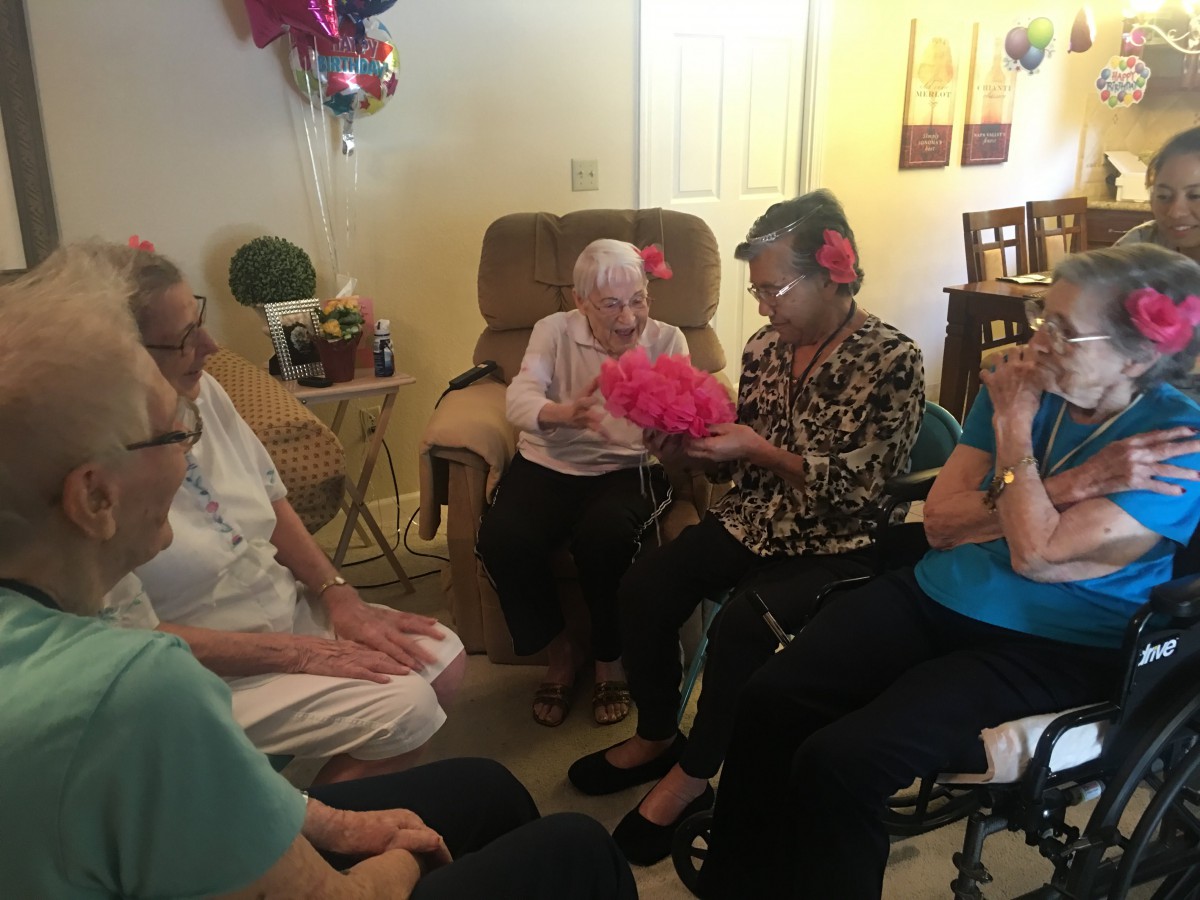 A group of seniors enjoying a festive gathering indoors with balloons and decorations.