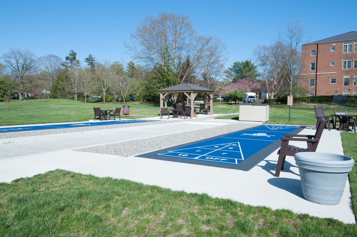 An outdoor shuffleboard court with a gazebo and benches in a park setting.