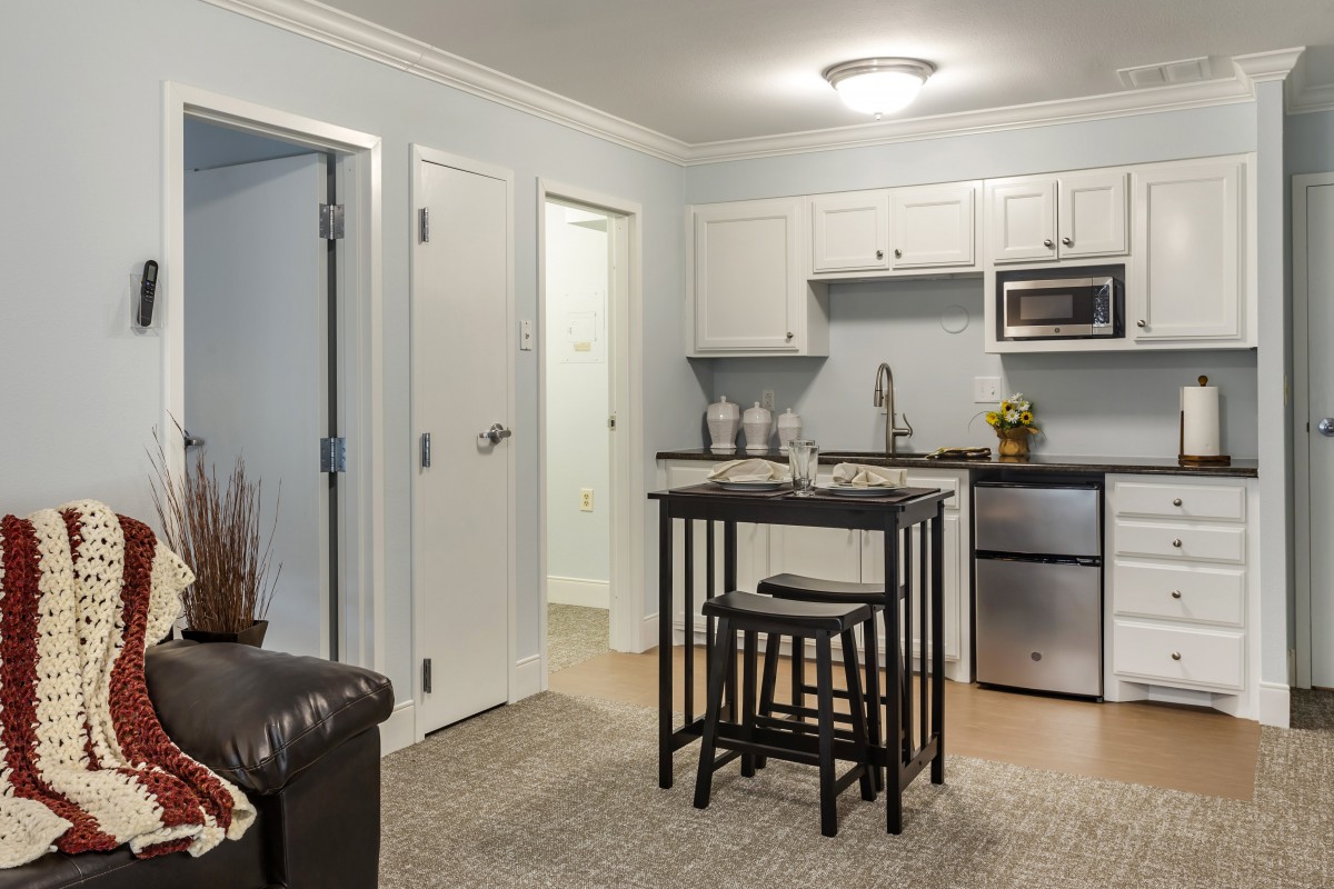 A modern apartment kitchen and dining area with a small table and stools.