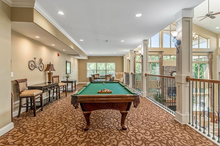 A spacious recreation room featuring a billiards table and comfortable seating.