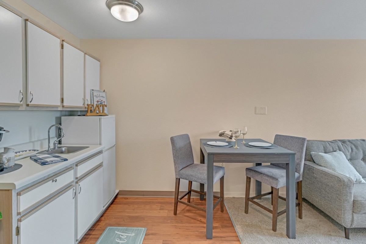 A small kitchen and dining area with a table, chairs, and cabinets.