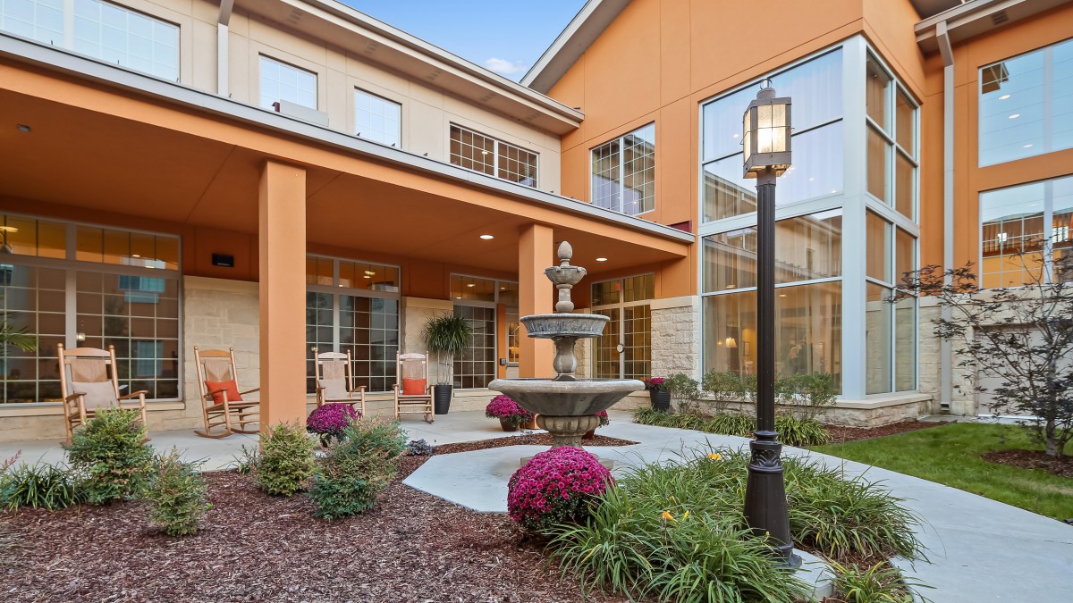 A well-maintained courtyard featuring a central fountain surrounded by flowering plants and modern architecture.