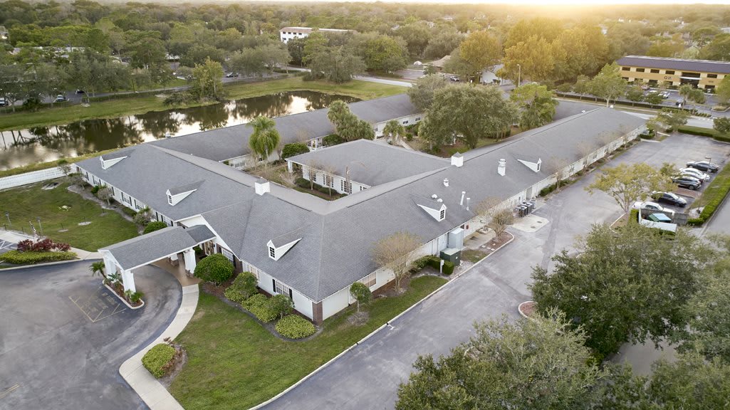 Aerial view of a residential building surrounded by trees and greenery.