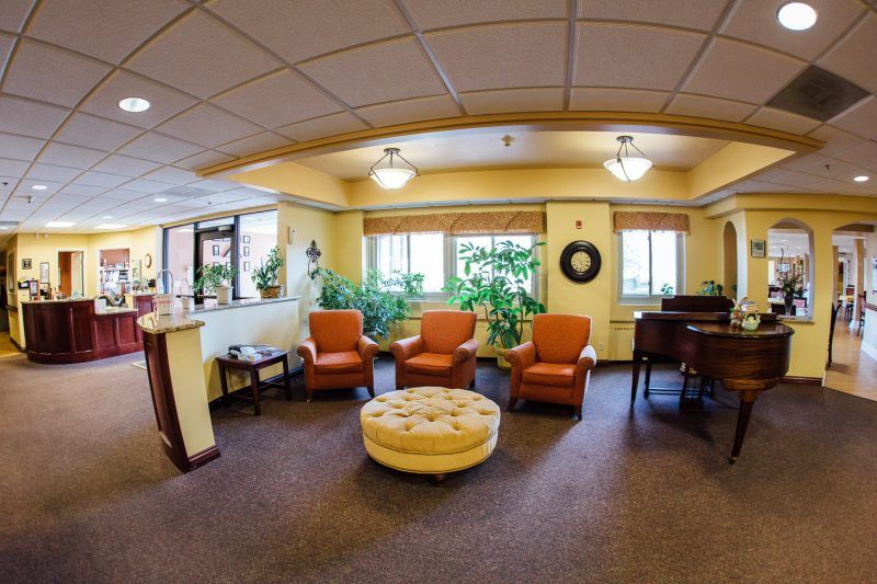 A cozy lobby area with seating arrangements and a piano, decorated with plants.