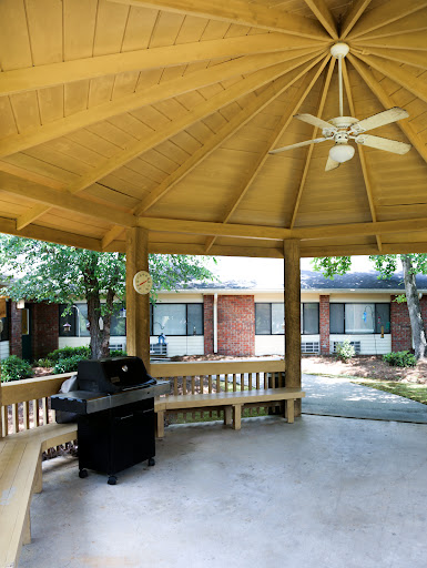 A spacious gazebo featuring a grill and ample seating, surrounded by greenery.