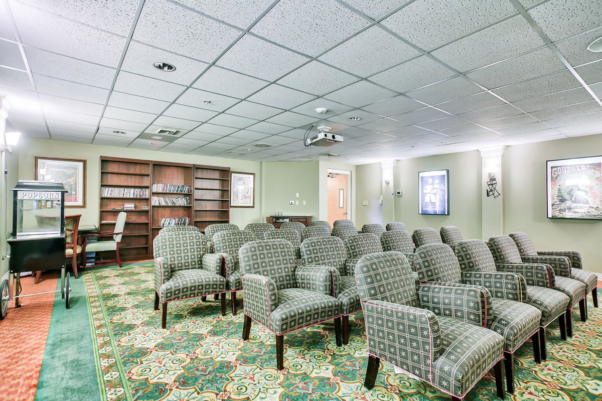 A well-furnished meeting room with patterned chairs, a projector, and bookshelves.