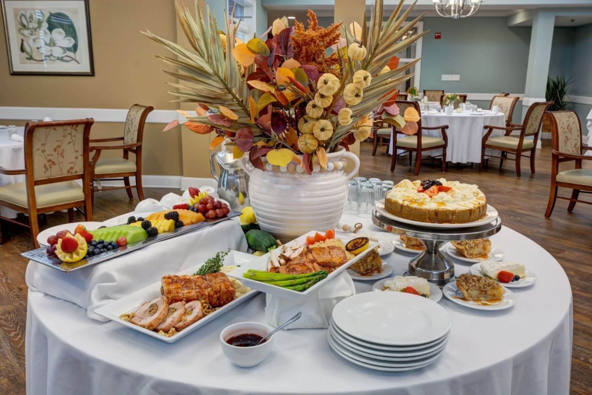 An elegant buffet table showcasing a variety of foods, desserts, and a vibrant floral arrangement.