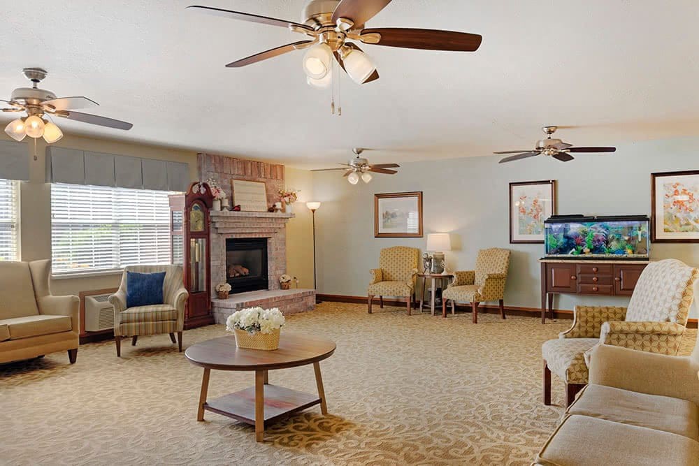 A spacious living room featuring a cozy fireplace, multiple ceiling fans, and comfortable seating.