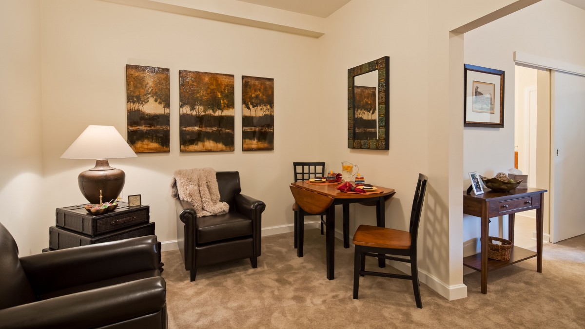 Cozy living room with armchairs, a small dining table, and wall art.