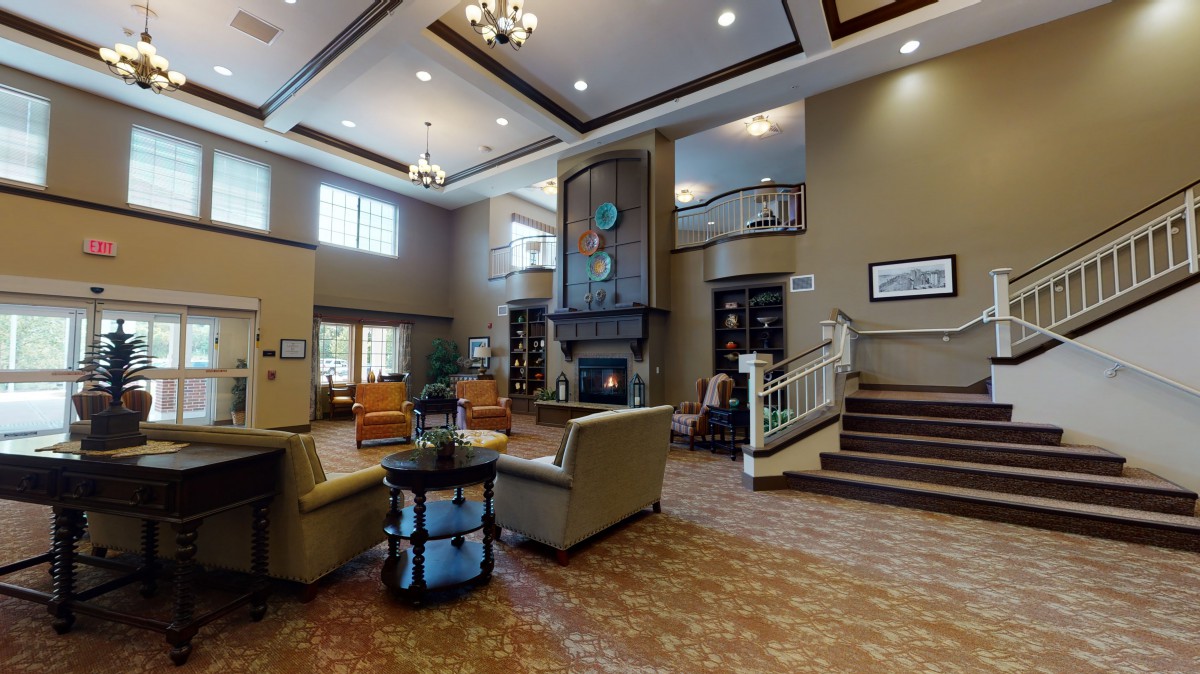 A modern lobby interior with comfortable seating, a fireplace, and elegant chandeliers.