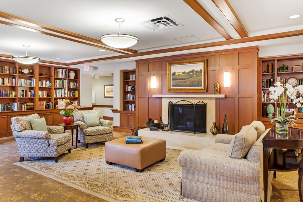 A cozy living room with a fireplace, comfortable sofas, and elegant wood paneling.