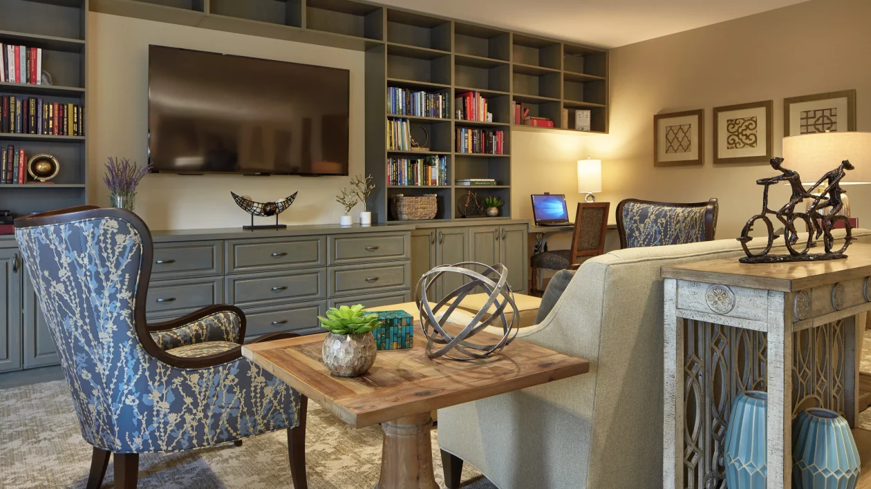A cozy living room with a large bookshelf, TV, and comfortable seating.