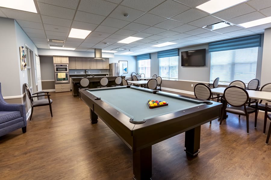A recreational room featuring a pool table, seating area, and a television.