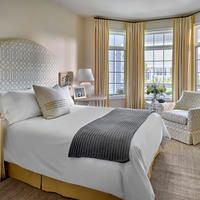 A cozy bedroom with a large bed, light curtains, and plenty of natural lighting.