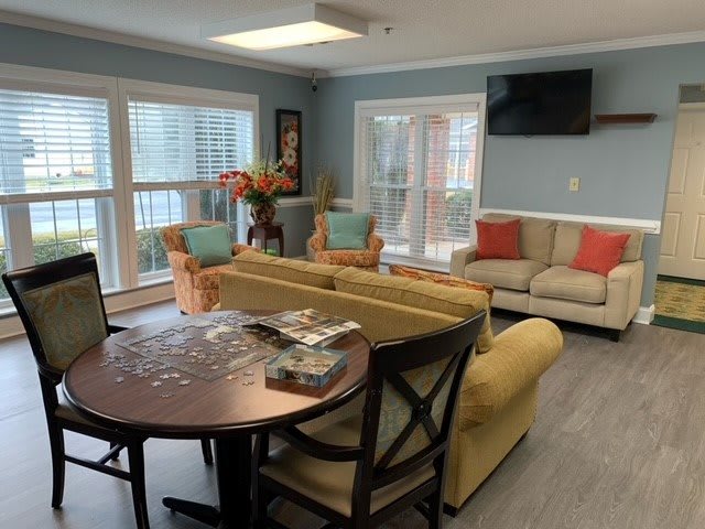 Cozy living room with comfortable seating, a television, and large windows.
