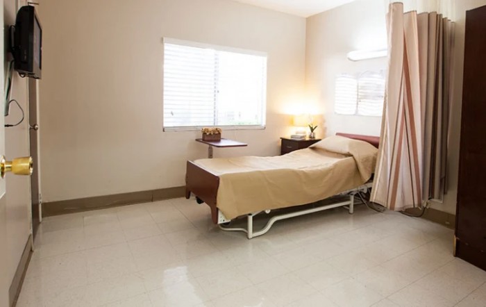 A clean and tidy hospital room with a bed, window, and a lamp on a bedside table.