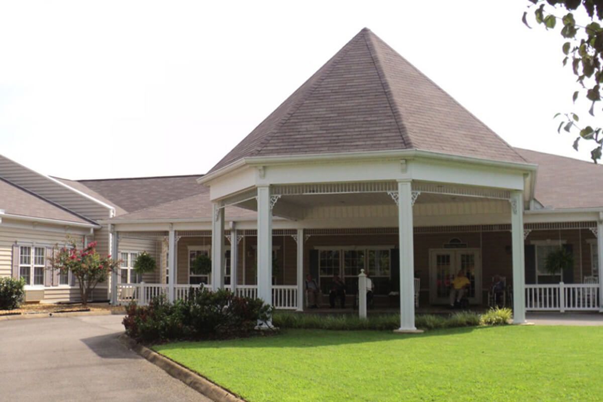 A building with a prominent entrance featuring columns and well-maintained landscaping.