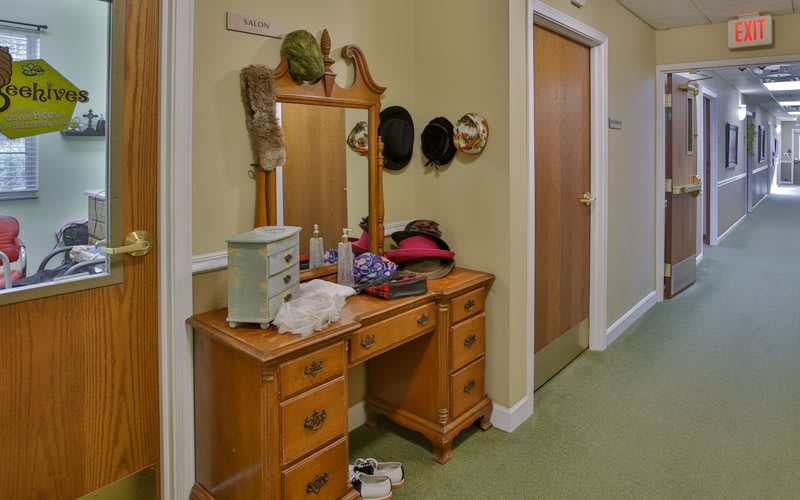 A wooden vanity with a mirror in a hallway, adorned with hats and various items.