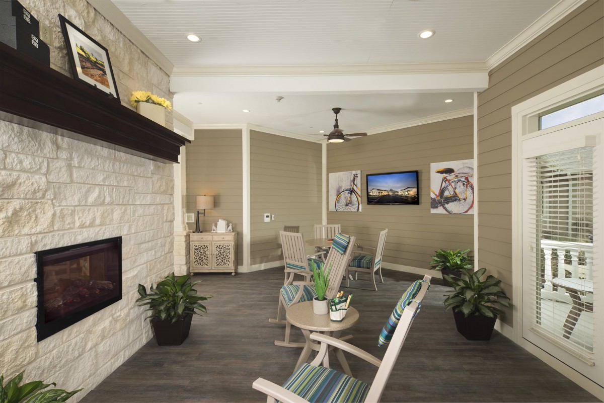 A cozy living room with modern decor, featuring a fireplace, seating area, and wall-mounted television.