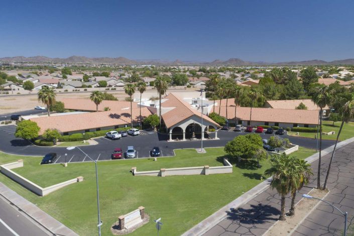 Aerial view of a church surrounded by palm trees and a suburban neighborhood.
