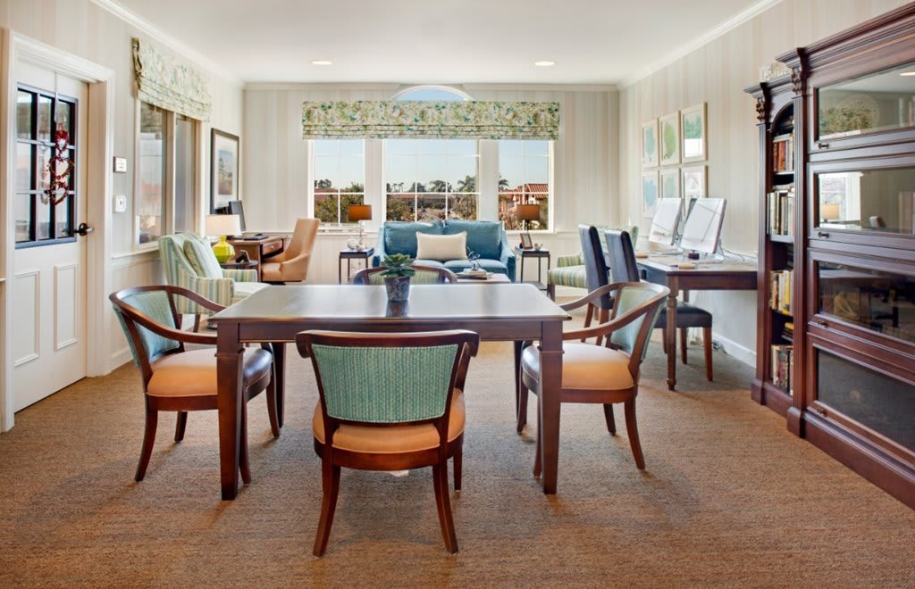 A stylish living room with a dining area, featuring elegant furniture and large windows.