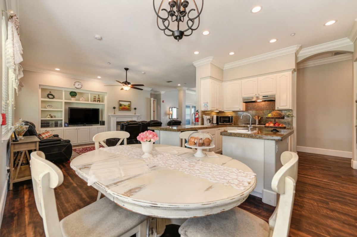 A modern open-concept kitchen and dining area with a round table and chandelier.