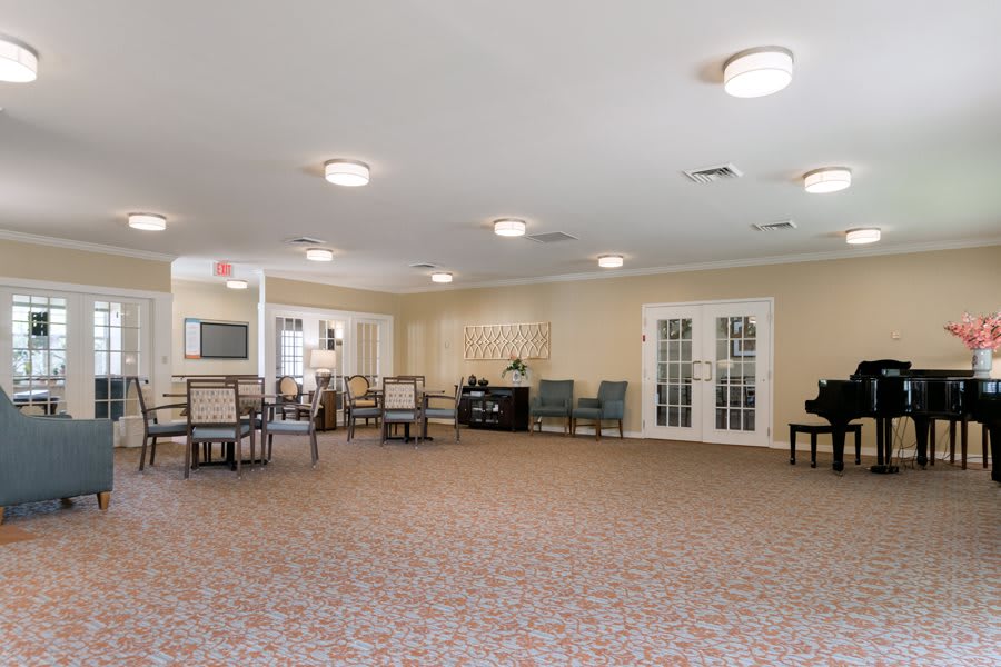 A spacious multi-purpose room with tables and chairs, suitable for meetings or gatherings.