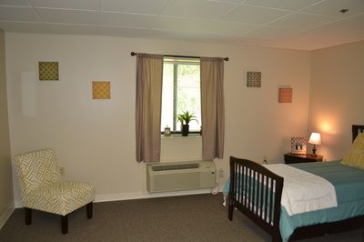 A cozy bedroom with a bed, chair, window, and simple decor.