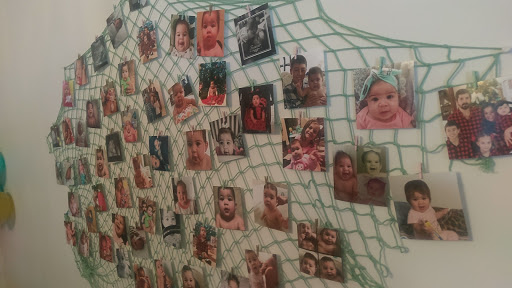 A collage of various photographs depicting faces, arranged on a wall behind a net.