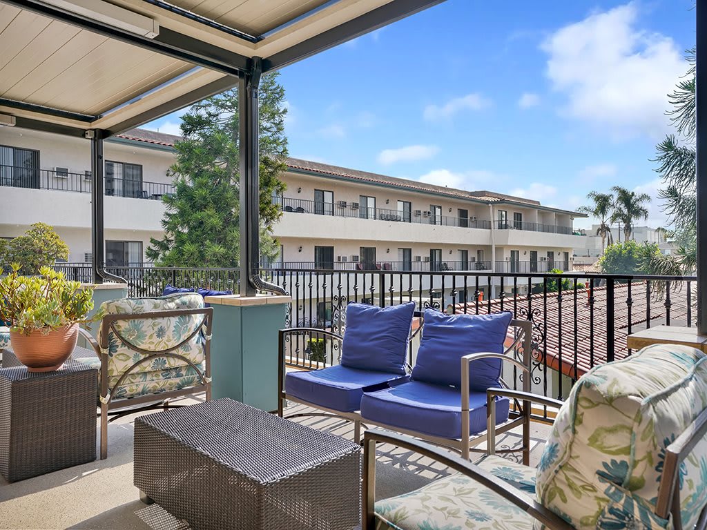 A cozy balcony with comfortable seating and a view of the apartment complex.