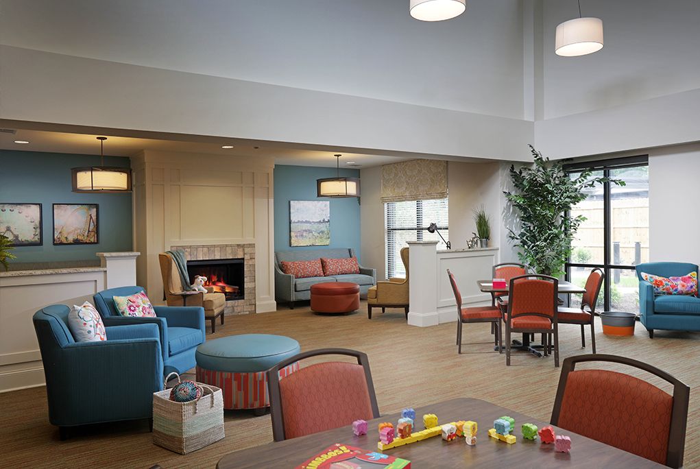 A cozy living room with modern furniture and a fireplace, featuring a seating area and children's toys.