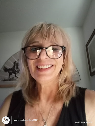 A cheerful woman with glasses smiling for the camera, captured indoors.