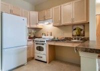 A cozy kitchen with light wooden cabinets, a refrigerator, and an oven.
