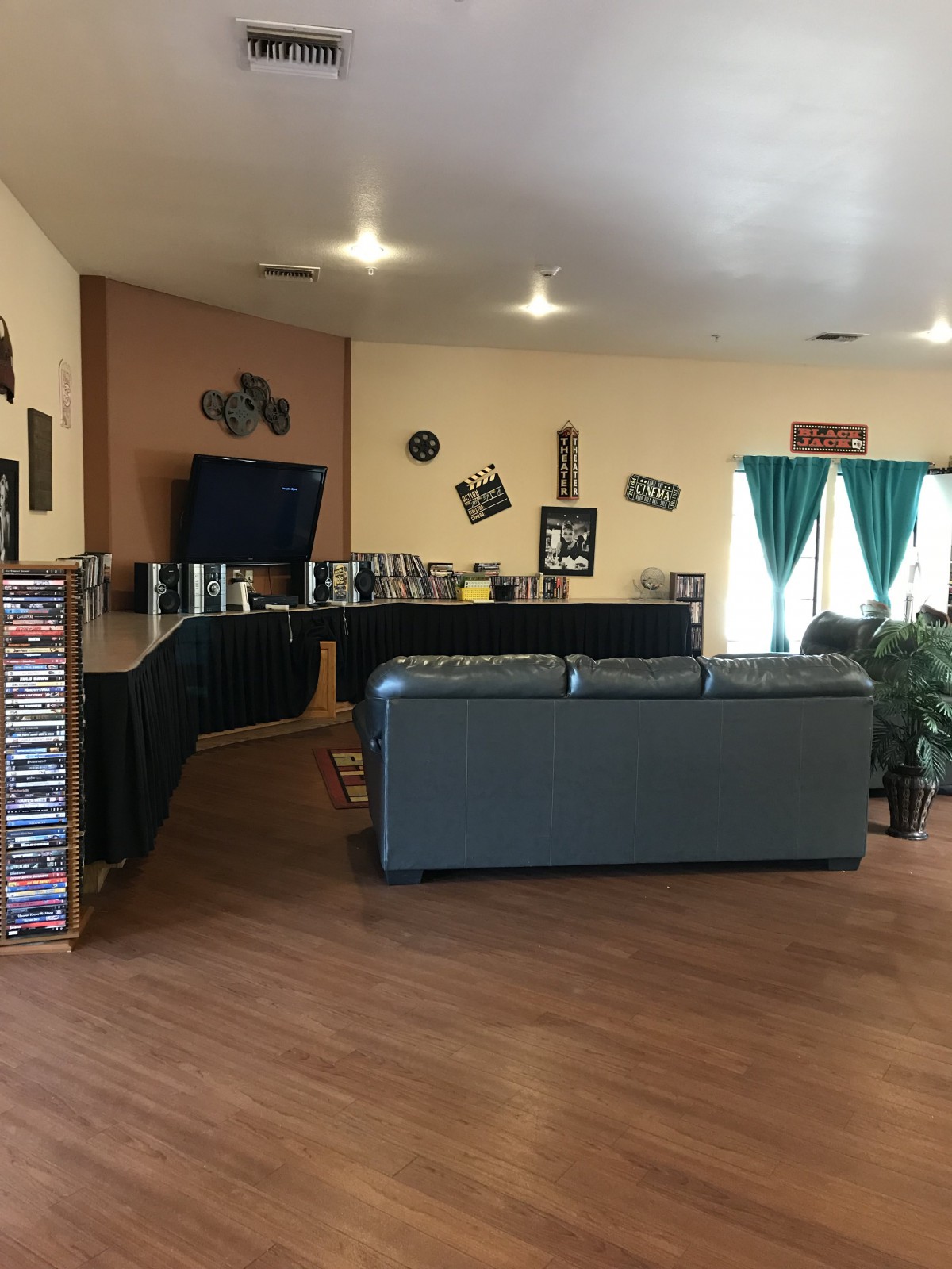 A cozy living room with a couch facing a television, surrounded by shelves and home decor.