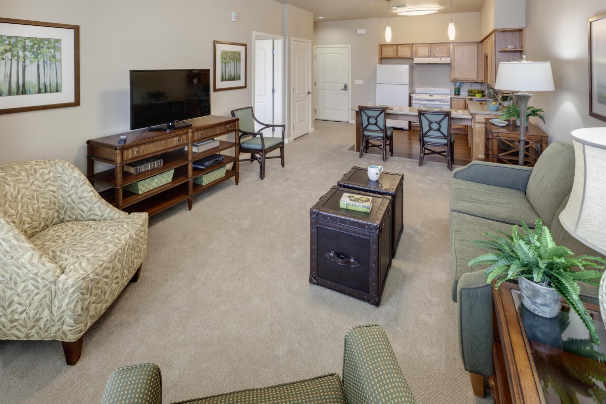 A spacious living area with an open kitchen and dining setup, featuring comfortable seating and modern appliances.