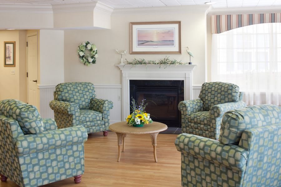 A cozy living room with patterned armchairs, a fireplace, and a coffee table adorned with flowers.