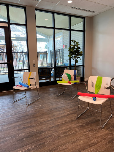 A setup for a fitness class featuring chairs with exercise bands and pool noodles in a bright indoor environment.