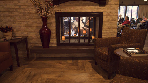A cozy living room featuring a decorative fireplace, a comfortable chair, and elegant floral accents.