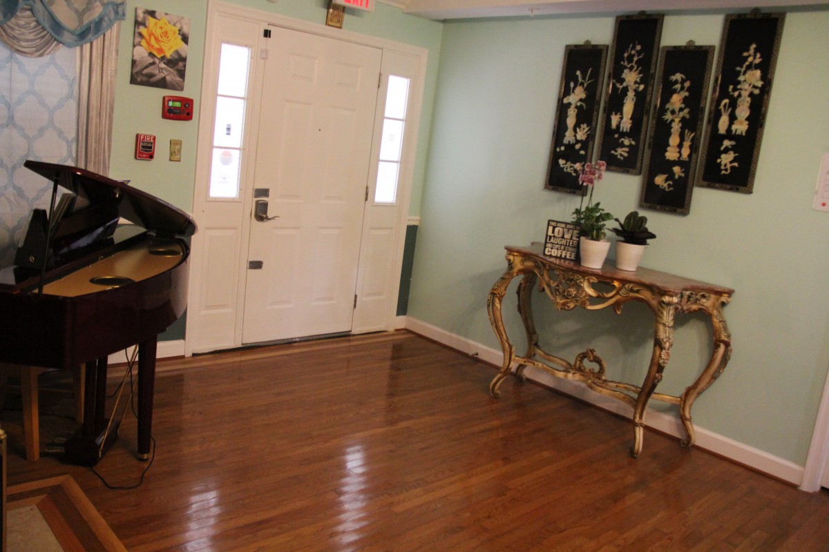A well-decorated entryway with a door, side table adorned with plants and decorative items, and artwork on the walls.