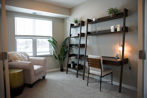 A cozy and modern home office setup, featuring a comfortable chair, stylish desk, and decorative shelves.