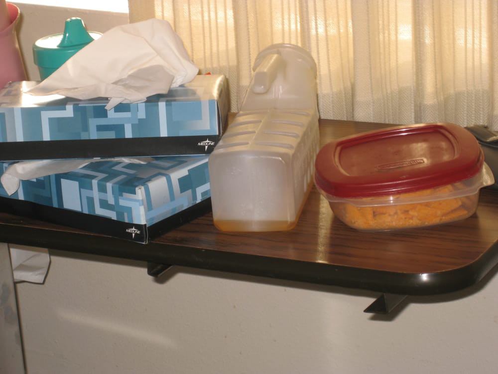A table with tissue boxes, a juice container, and a food storage container.