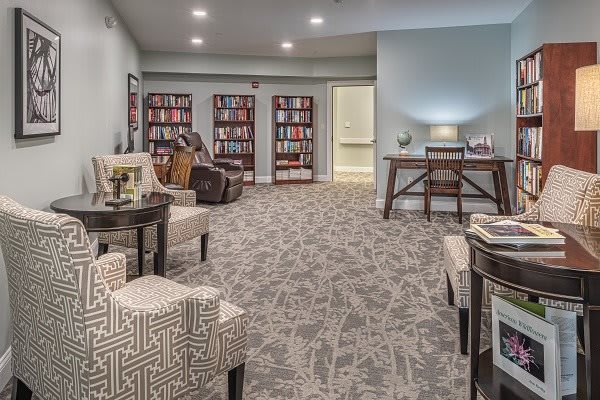 A cozy library space with bookshelves, comfortable seating, and an office desk.