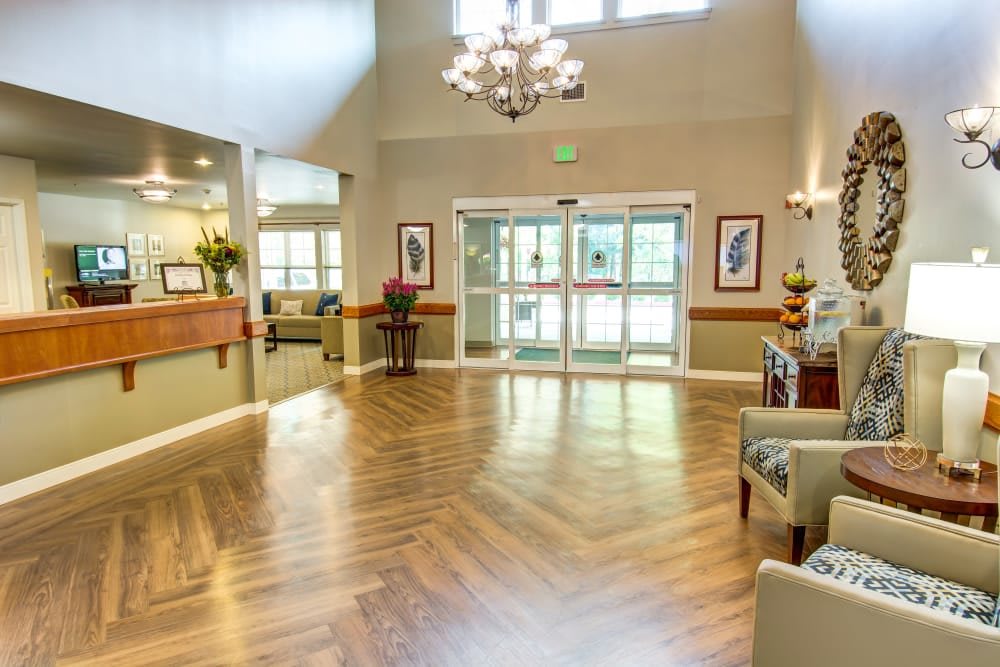 A bright and modern lobby with wood flooring and a chandelier.