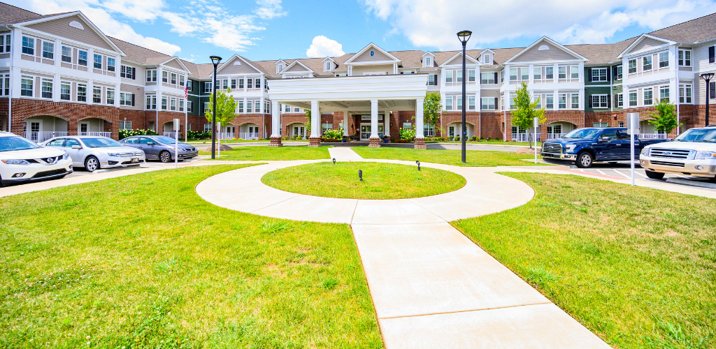 A modern building with a circular walkway and well-maintained lawn under a bright blue sky.