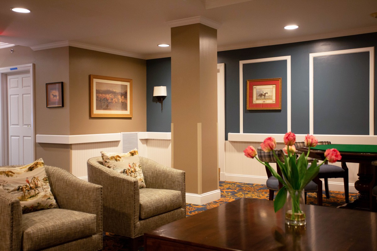 A cozy living room with comfortable seating, decorative artwork, and a vase of tulips on the table.